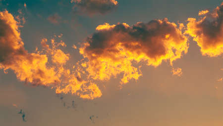 Fluffy clouds lit by the colors of the sunset. No land view, only sky.の写真素材