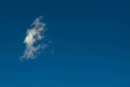 An isolated cloud in the shape of a face on the blue skyの写真素材