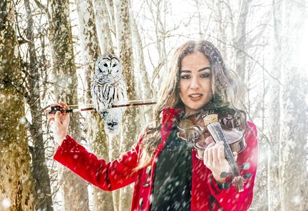 Beautiful girl posing with a violine in a winter ambientの写真素材