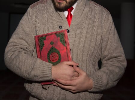 Muslim man holding Koran in hands