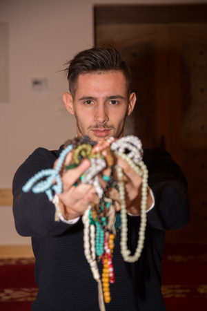 Young muslim man holding lot of tasbih in handsの写真素材