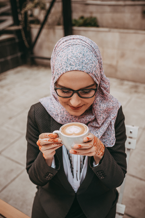Young muslim girl typing on laptop and drink coffeeの写真素材