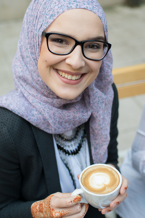 Young muslim girl typing on laptop and drink coffeeの写真素材