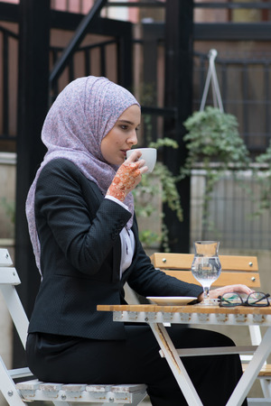 Young muslim girl typing on laptop and drink coffeeの写真素材