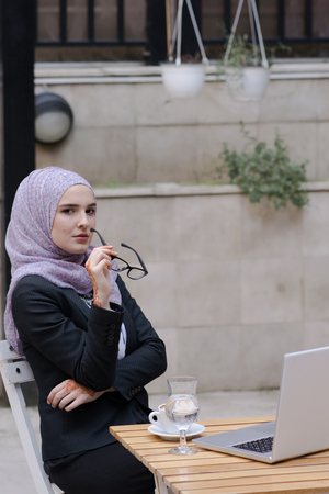 Young muslim girl typing on laptop and drink coffeeの写真素材