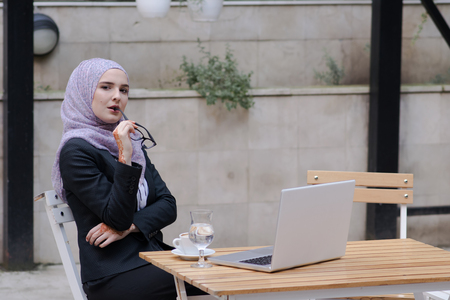 Young muslim girl typing on laptop and drink coffeeの写真素材