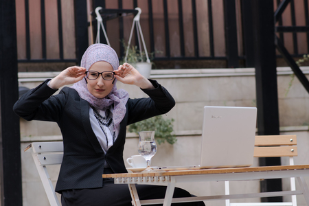 Young muslim girl typing on laptop and drink coffeeの写真素材