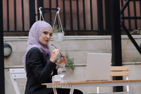Young muslim girl typing on laptop and drink coffeeの写真素材