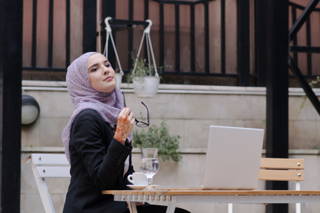 Young muslim girl typing on laptop and drink coffeeの写真素材