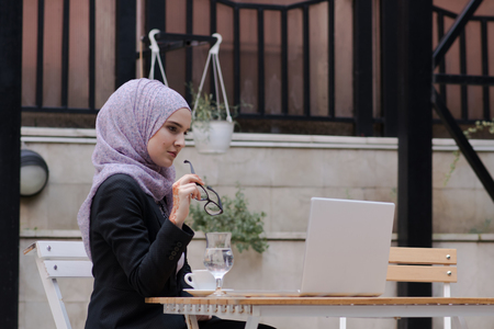 Young muslim girl typing on laptop and drink coffeeの写真素材