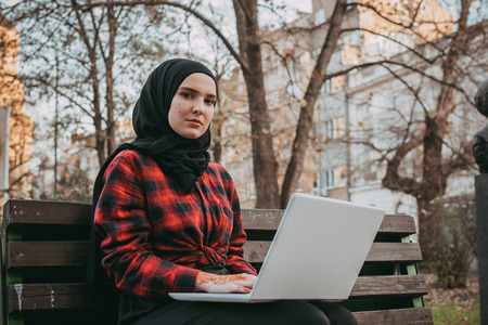 Young muslim girl typing on laptop and drink coffeeの写真素材