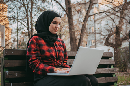Young muslim girl typing on laptop and drink coffeeの写真素材