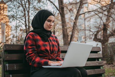 Young muslim girl typing on laptop and drink coffeeの写真素材