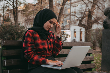 Young muslim girl typing on laptop and drink coffeeの写真素材
