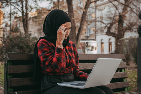 Young muslim girl typing on laptop and drink coffeeの写真素材