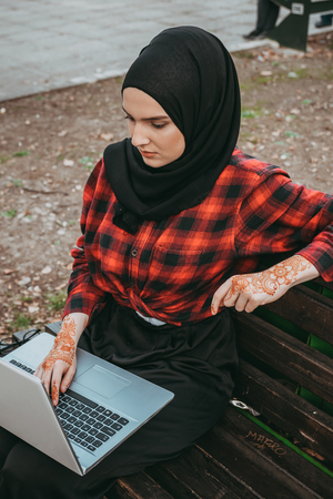 Young muslim girl typing on laptop and drink coffeeの写真素材