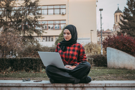 Young muslim girl typing on laptop and drink coffeeの写真素材