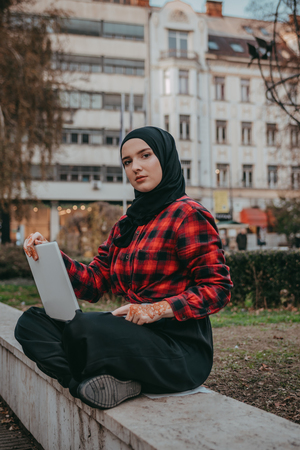Young muslim girl typing on laptop and drink coffeeの写真素材