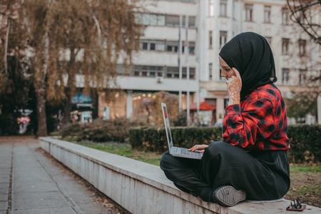 Young muslim girl typing on laptop and drink coffeeの写真素材
