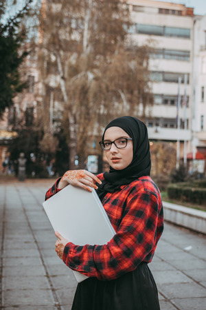 Young muslim girl typing on laptop and drink coffeeの写真素材