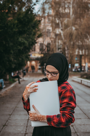Young muslim girl typing on laptop and drink coffeeの写真素材