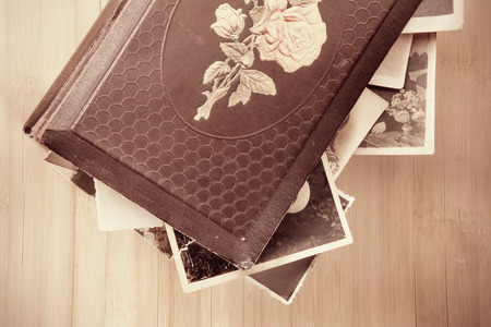 Old photo-album with retro pictures inside it on wooden background.の写真素材