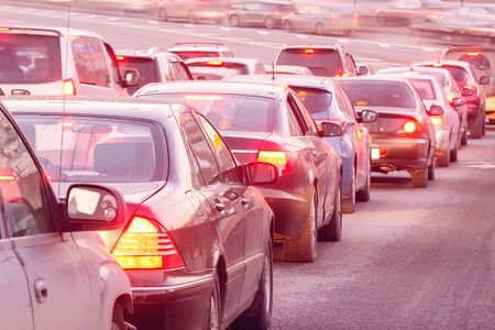 Cars stand before the trafficlight on the central city streets at sunset time.