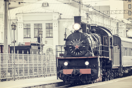 Retro steam train departs from the station.の写真素材