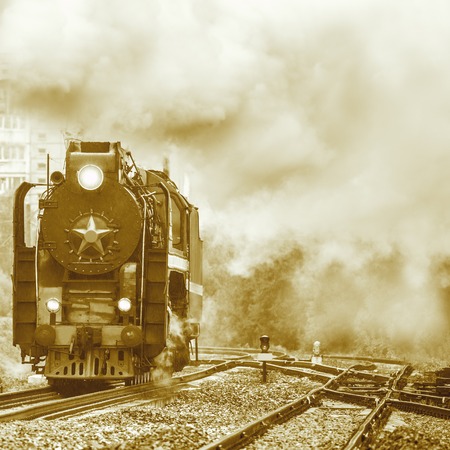 Old retro steam locomotive moves under the pouring rain.の写真素材
