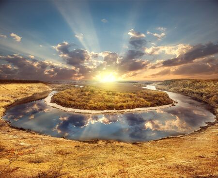 Autumn view of the river from the high hill at sunset time.の写真素材