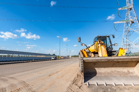 Yellow bulldozer by the new road during construction process.