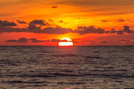 Vintage style image of the sunset sky over the calm surface of the sea.の写真素材