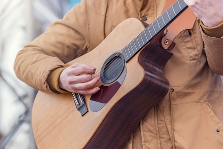 Man's hands playing acoustic guitar on the stage.