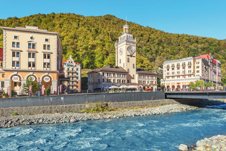 Krasnaya Polyana, Russia., October 10, 2019: Hotels, shops and restaurants along Mzymta river at autumn sunny day time.のeditorial素材