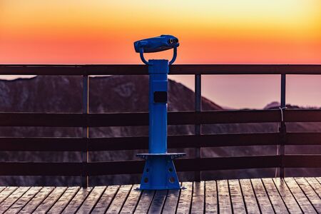 Binoculars on the mountain viewpoint at sunset time.の写真素材