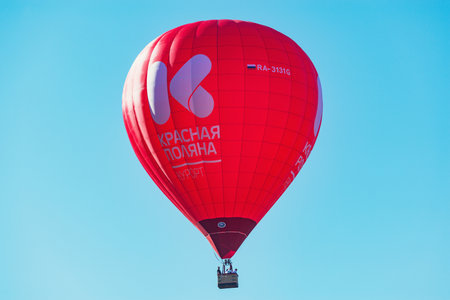 Krasnaya Polyana, Russia - October 13, 2019: Red hot air balloon above the town on the blue sly background.のeditorial素材