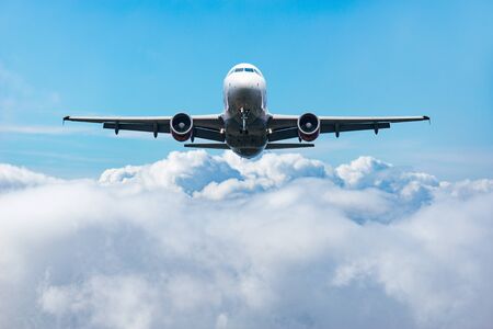 Flight of the passenger plane above the clouds at day time.