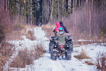 Family on the ATV Quad Bikes on the winter road.