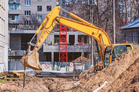 Excavator digs a hole on the construction site territory.
