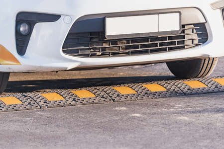 Car approaches to the traffic safety speed bump on the asphalt road.の写真素材
