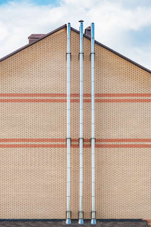 Steel metal chimney pipe on the wall of the house.の写真素材