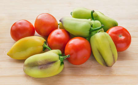 Red fresh tomatoes and green sweet pepper on wooden table.の写真素材