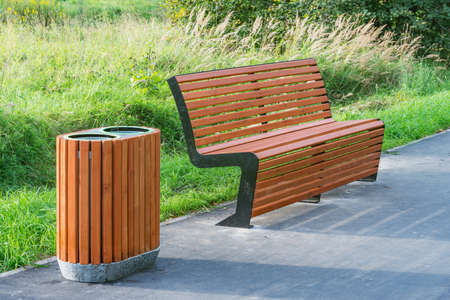 Bin for waste collection wooden bench in the city park at sunset time.の写真素材
