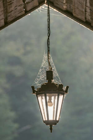 Old ancient lantern with spiderweb under the roof.の写真素材