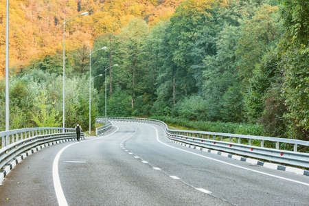 Man walks along the highway in the mountains at sunset time.の写真素材