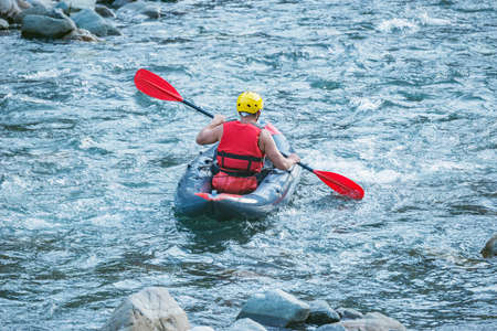 Man floats by inflatable boat on the mountain river.の写真素材