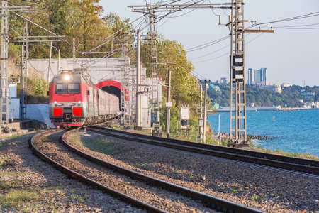 Passenger train moves from the tunnel along Black sea. Sochi. Russia.の写真素材