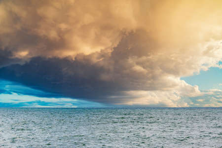 Stormy sky over the calm surface of the sea at sunset time.の写真素材