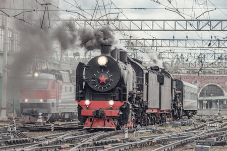 Electric and steam trains depart from the station.の写真素材