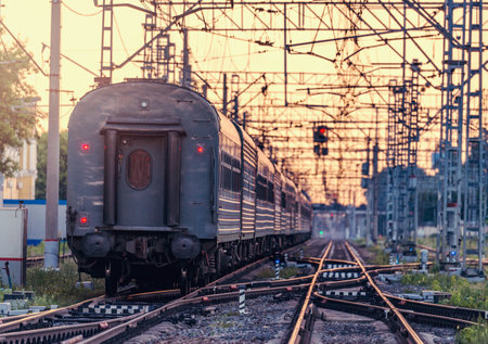 Passenger train departs from the station at sunset time.